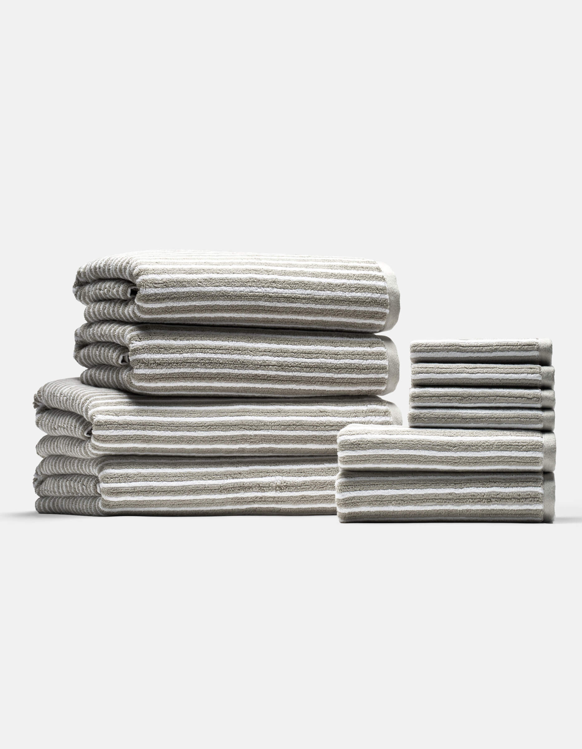The Cozy Earth Complete Ribbed Terry Bath Bundle features gray and white striped towels in various sizes, neatly folded and arranged into two stacks on a plain light background.
