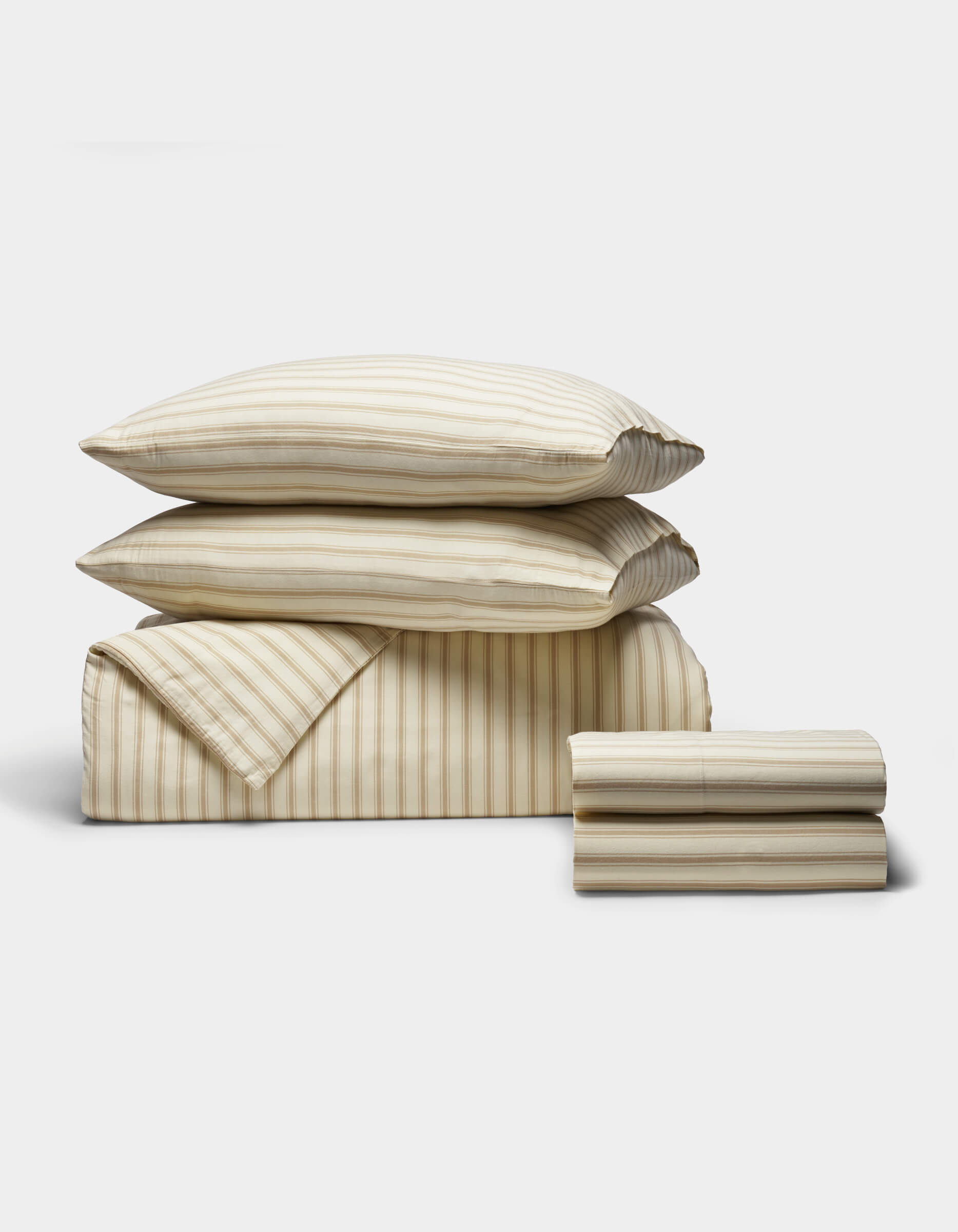 The Cozy Earth Soft-Wash Cotton Bedding Deluxe Bundle, featuring two pillows, a folded duvet, and two folded sheets in beige and white stripes, is neatly arranged against a plain white background.