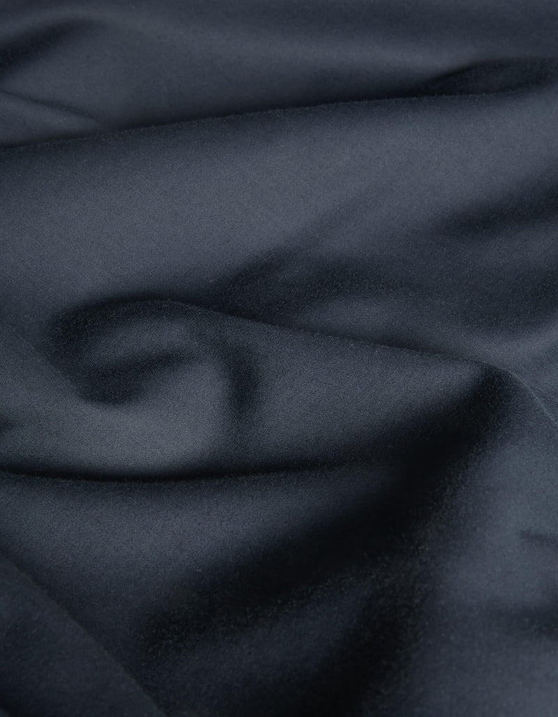 A close-up of Cozy Earth's Soft-Wash Cotton Flat Sheet reveals dark, smooth cotton with subtle folds and a soft, slightly glossy texture, creating a rich and elegant look.