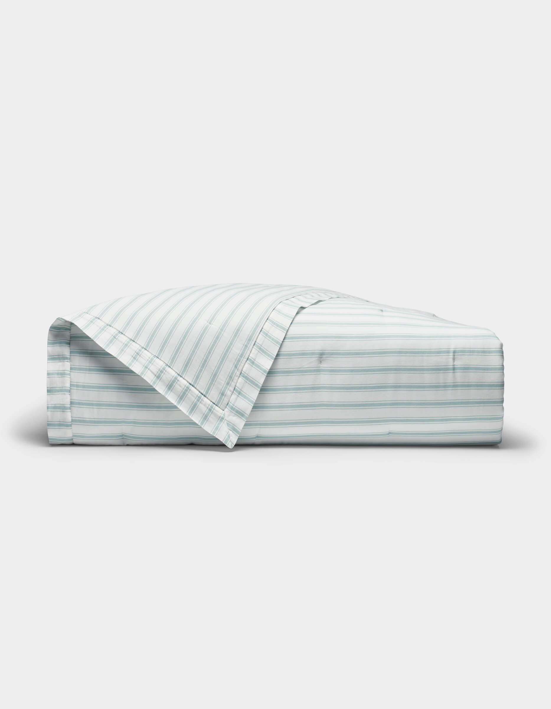 The Cozy Earth Soft-Wash Cotton Quilt is shown neatly folded with one corner turned back, revealing its light color and thin horizontal blue and gray stripes against a plain white background.