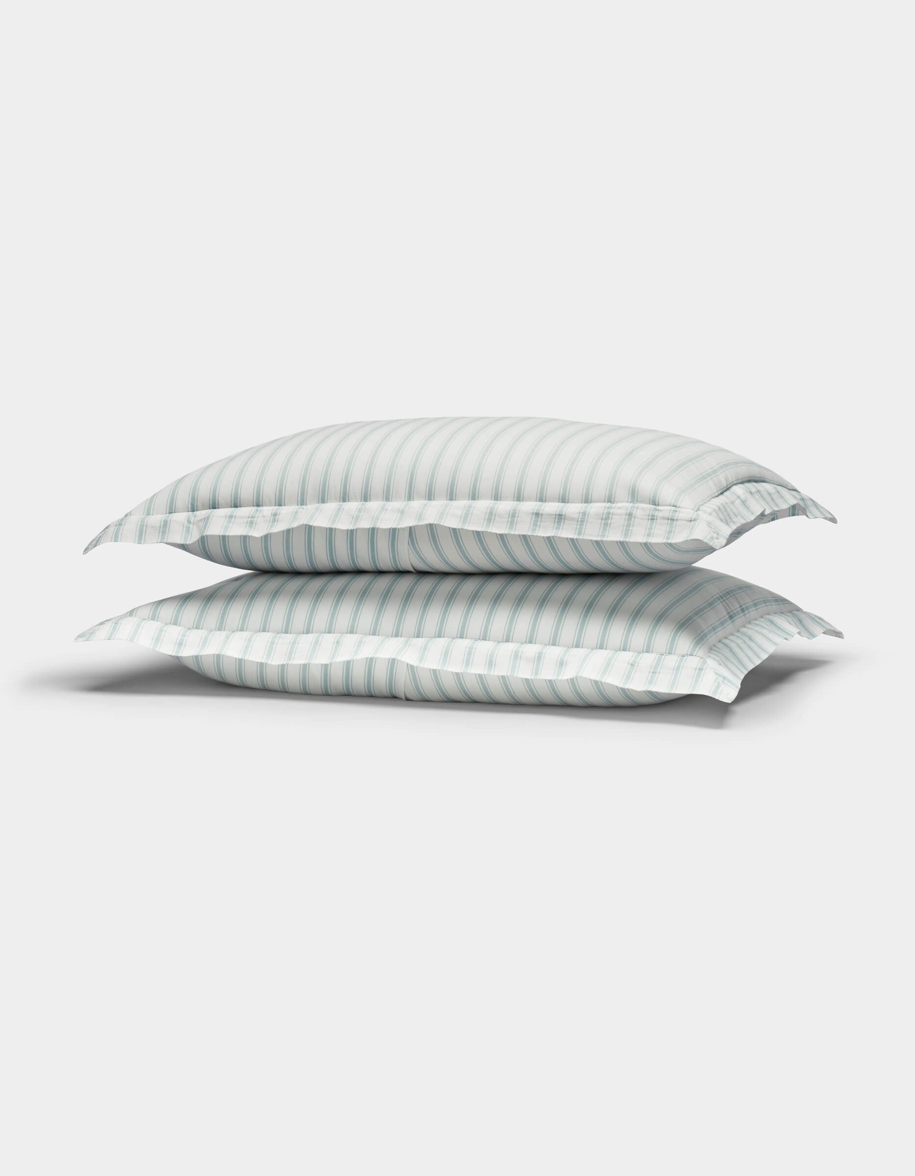 Two Cozy Earth Soft-Wash Cotton Quilted Shams in white with light blue and gray stripes are stacked together against a plain white background.|Color:River and Sea Salt Stripe