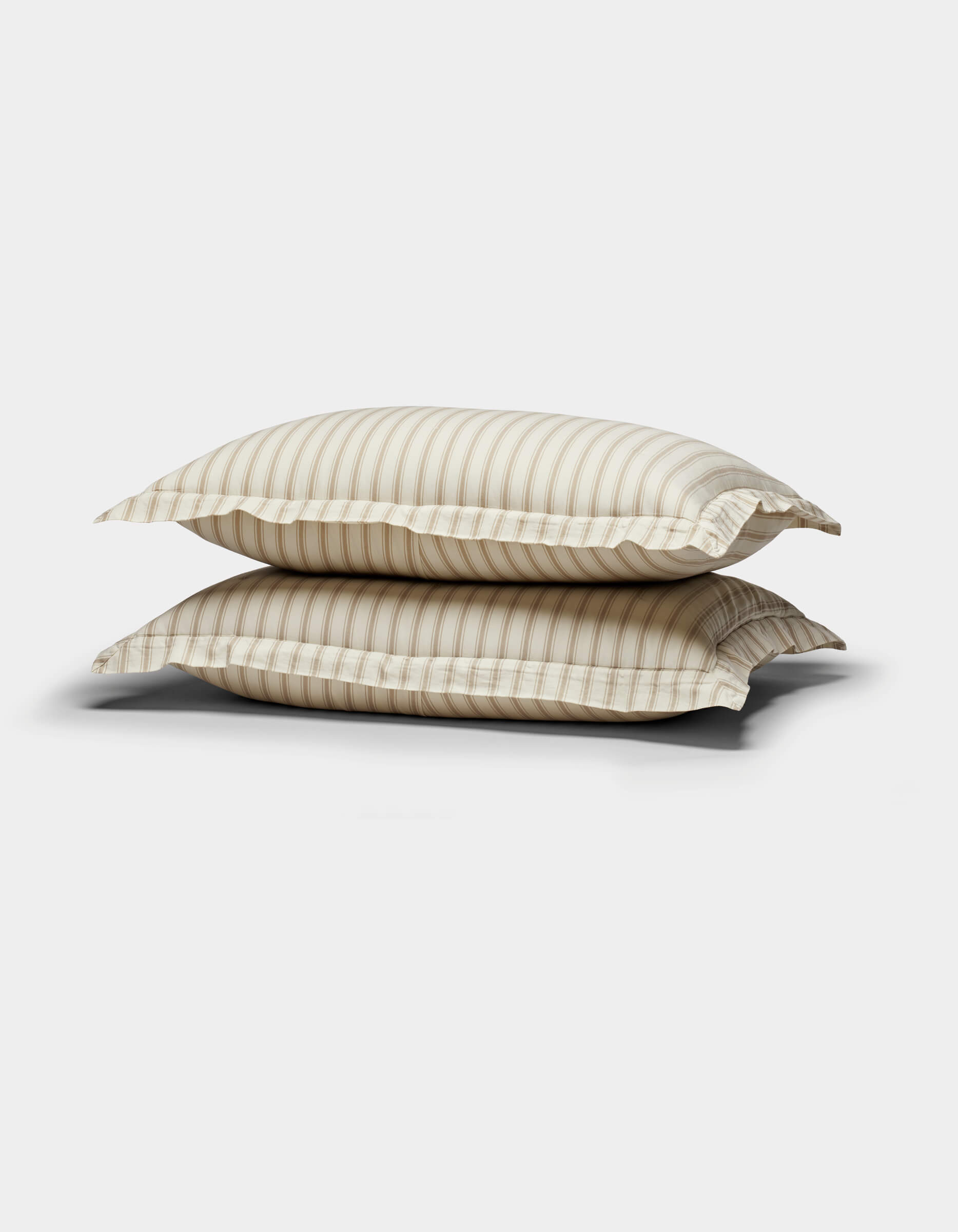 Two Soft-Wash Cotton Quilted Shams by Cozy Earth, in beige and white stripes, are stacked against a plain white background.