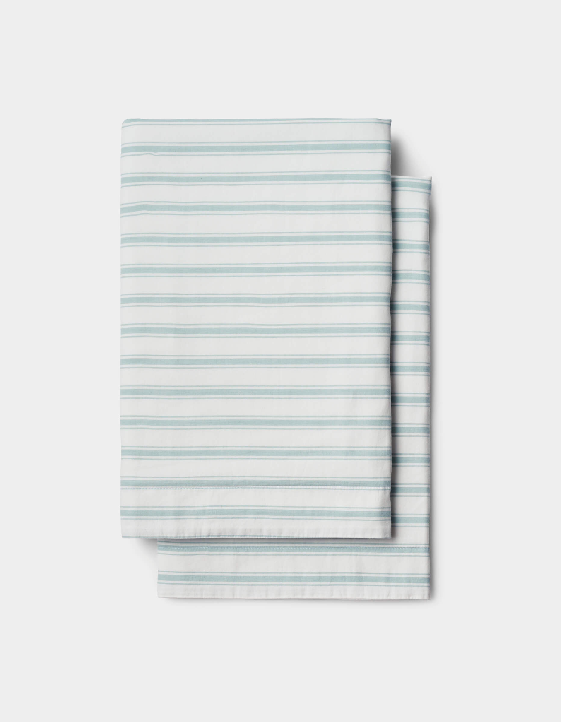 The Soft-Wash Cotton Sheet Set by Cozy Earth features a neatly folded white sheet with light blue horizontal stripes, displayed on a plain white background.