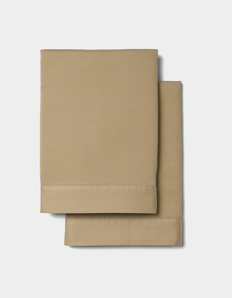 Two neatly folded Soft-Wash Cotton Shams by Cozy Earth, light brown in color, are stacked on a plain white background.