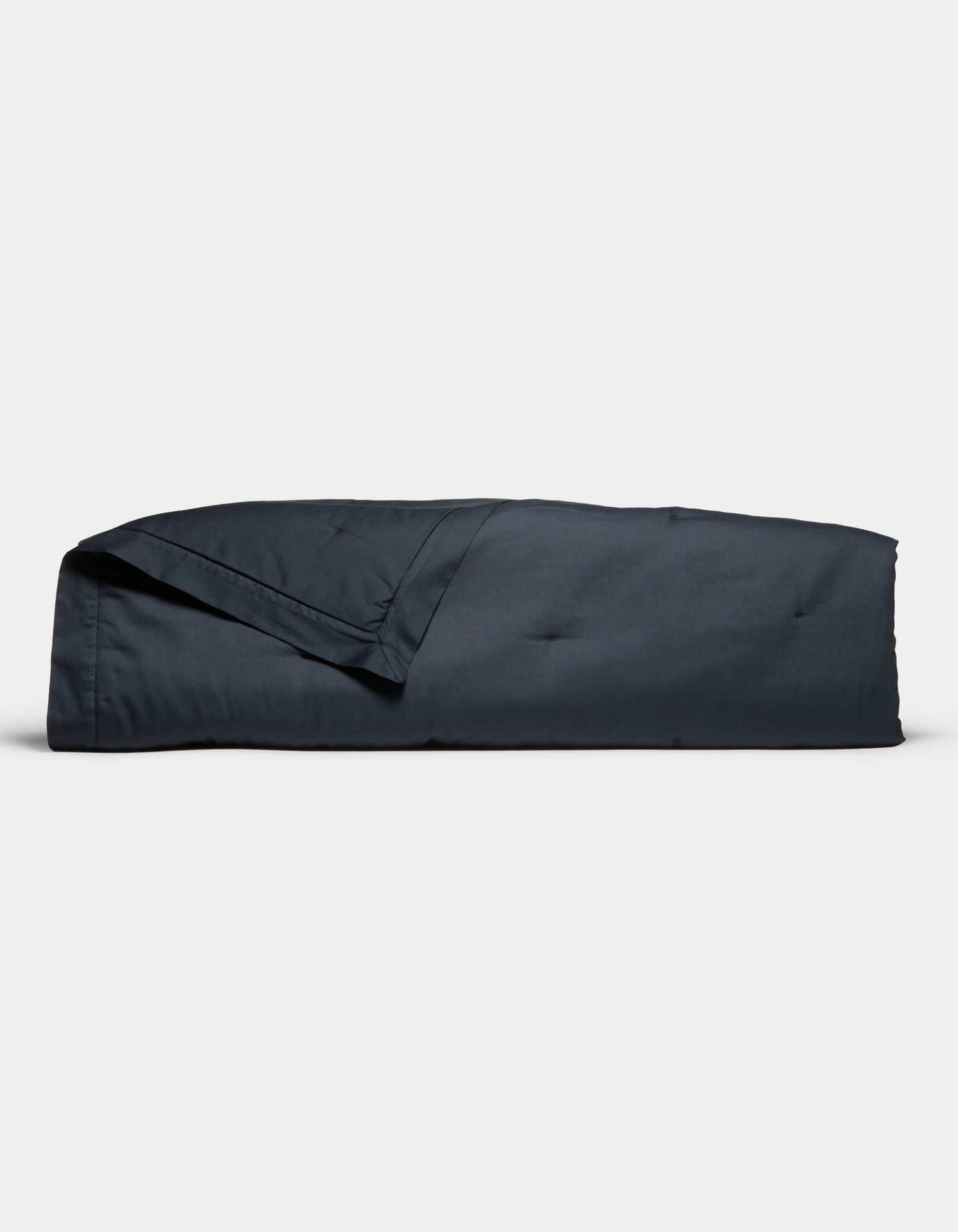 The Cozy Earth Soft-Wash Cotton Quilt set, in dark blue, is neatly folded and displayed against a plain white background. It includes a quilt and matching pillowcase, both looking soft and smooth.|Color:Eclipse