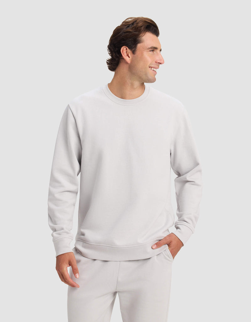 A man wears the Cozy Earth Men's Dylan Crewneck with matching sweatpants, smiling and looking to the side against a plain light background.