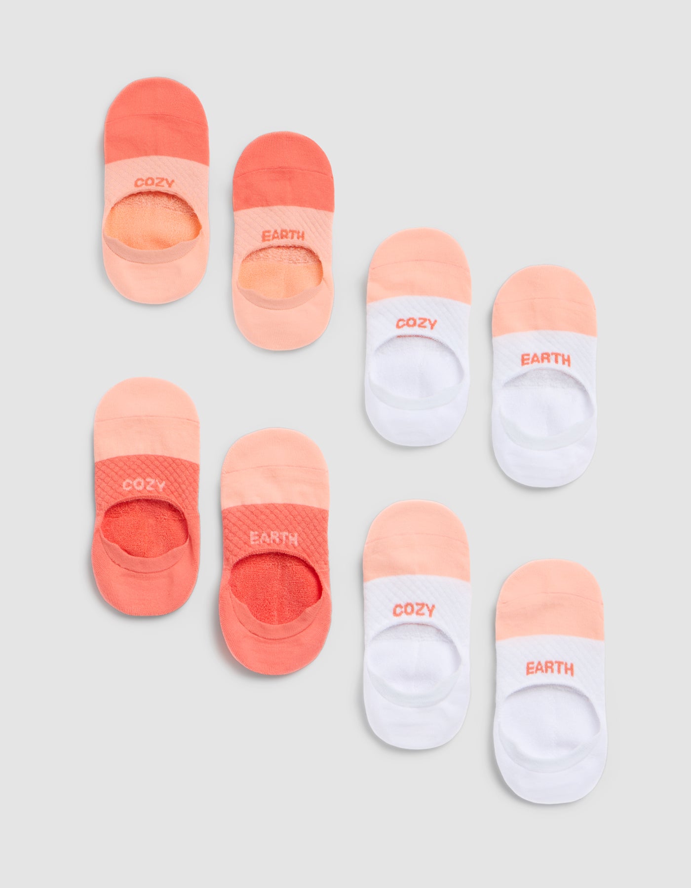 The Cozy Earth Essential No-Show Sock 4-Pack includes socks in peach, orange, and white tones with "COZY" or "EARTH" printed on the toes, shown arranged neatly on a light grey background. |Color:Cantaloupe