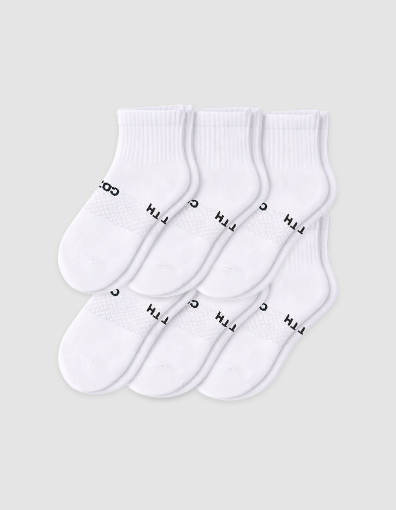 Six pairs of Cozy Earth Men’s Essential Quarter Socks in white are neatly displayed on a plain background, each featuring a ribbed cuff and black text by the toes.