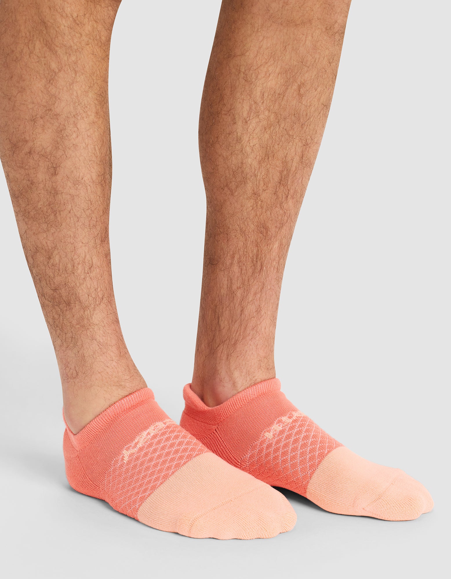 A close-up of a person's lower legs and feet wearing Cozy Earth Essential Ankle Socks in pink, standing on a light gray surface. |Color:Cantaloupe