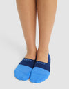 A person stands with feet together, wearing Cozy Earth Essential No-Show Socks in bright blue and navy with "COZY EARTH" displayed on top, against a plain white background. |Color:Harbor