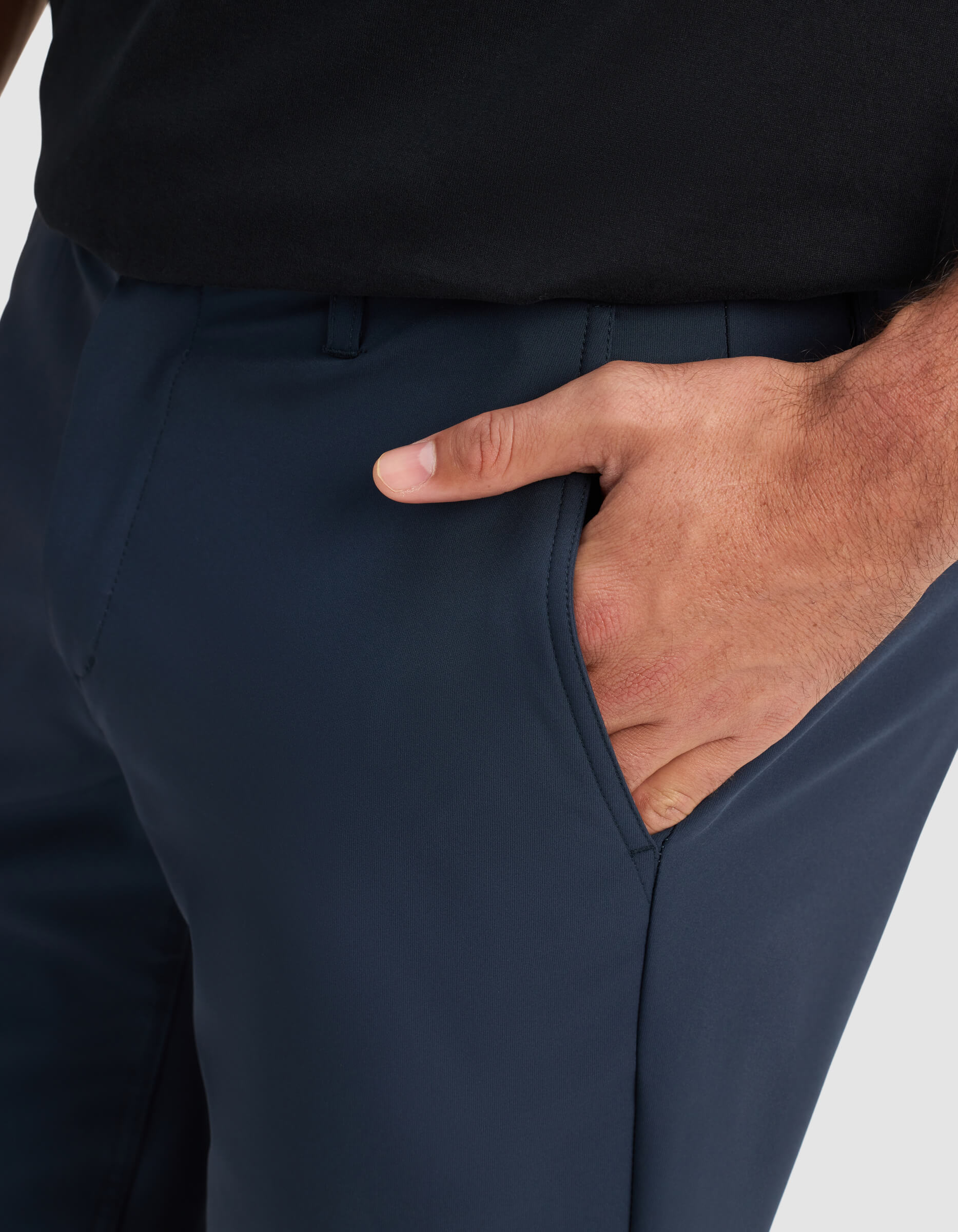 A close-up of a person wearing Cozy Earth Men's Everywhere Short in dark blue and a black shirt, with their right hand placed inside the short’s pocket.