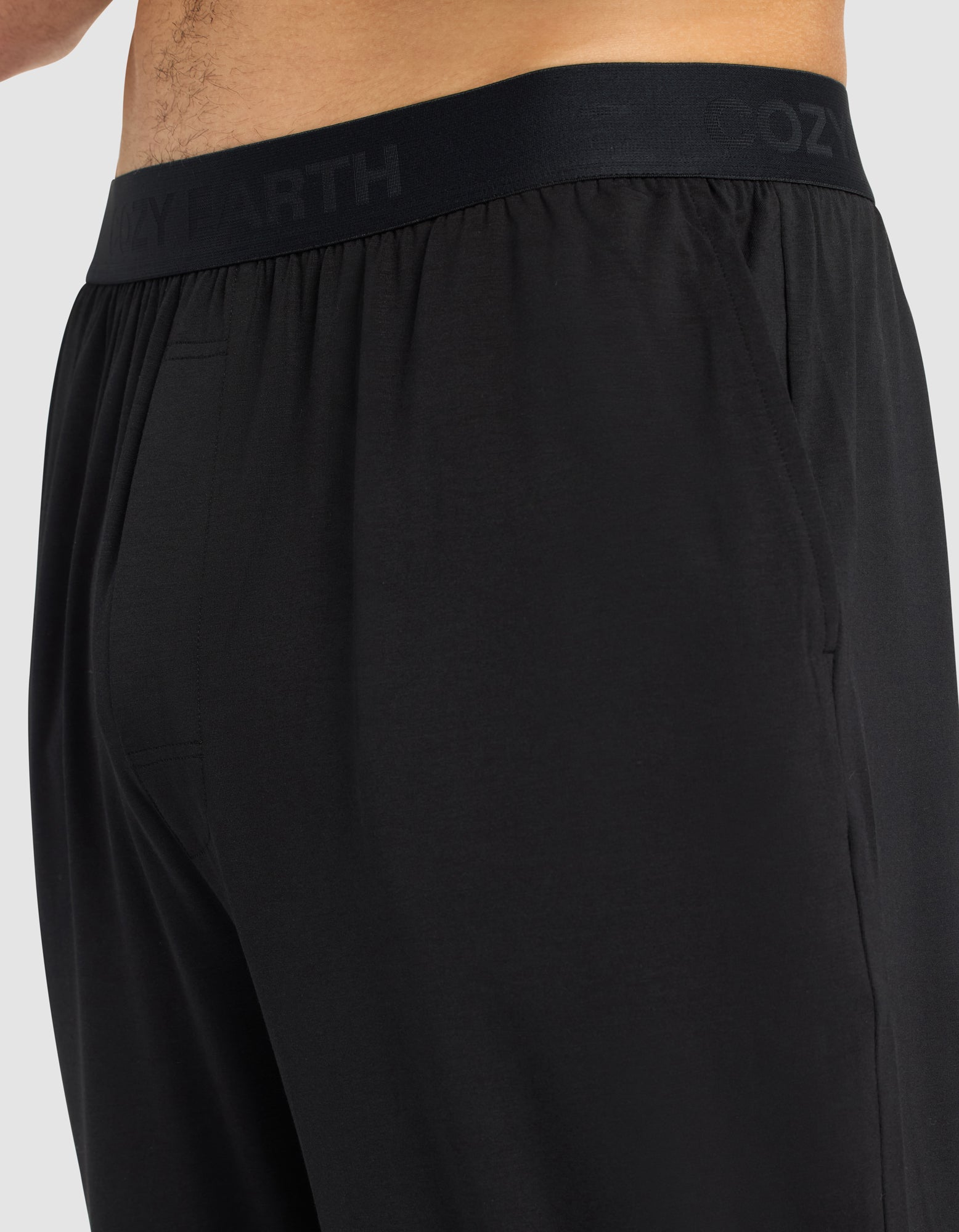 Close-up side view of a person wearing Cozy Earth Men's First Layer Pajama Pant, featuring an elastic waistband subtly printed with "COZY EARTH." The soft, smooth fabric enhances comfort.