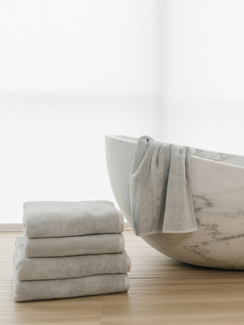 Complete Ribbed Terry Bath Bundle in the color Light Grey. Photo of Complete Ribbed Terry Bath Bundle taken in a bathroom next to a bathtub.