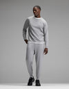 A man stands against a plain gray background wearing the Cozy Earth Men’s Brushed Bamboo Jogger Set in light gray, paired with black sneakers, looking to his left with one hand in his pocket.|Color:Stone