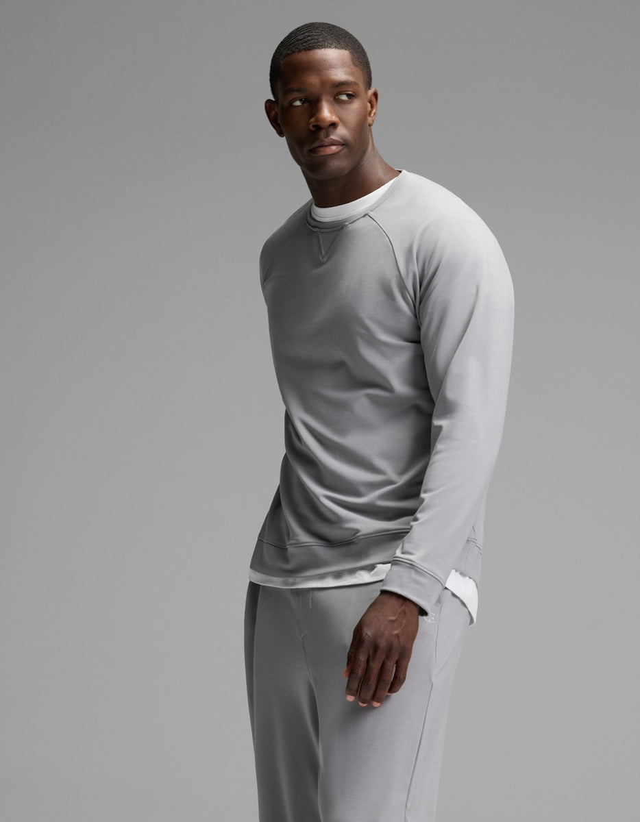 A man stands against a plain background, wearing the Cozy Earth Men’s Brushed Bamboo Jogger Set in light gray, with a white shirt peeking out underneath. He looks slightly to his left with a calm expression.