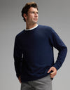 A man wears the Cozy Earth Men’s Brushed Bamboo Pullover Crew in navy, paired with gray pants, as he stands against a plain gray background and looks off to the side with one hand in his pocket.|Color:Navy