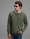 A man stands against a plain gray background with one hand in his jeans pocket, wearing dark sunglasses, a white T-shirt, and the Cozy Earth Men’s Brushed Bamboo Pullover Crew in Olive.|Color:Olive