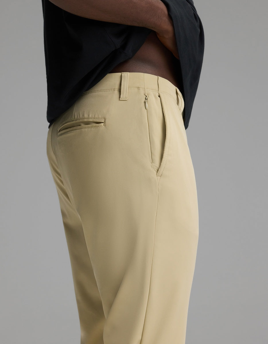 A man wearing Cozy Earth’s Men’s Everywhere Pant in light beige and a black shirt, shown from the side with hands in pockets against a plain gray background.