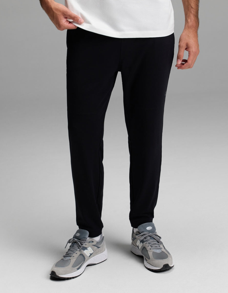 A person is shown from the waist down wearing Cozy Earth’s Men’s Recovery Jogger in black, standing against a plain gray background.|Color:Black
