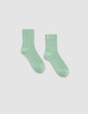 A pair of Plush Lounge Quarter Sock by Cozy Earth, in light green ribbed fabric, is laid flat on a plain white background with one sock slightly angled outward.|Color:Wintergreen