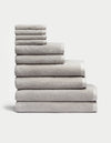 The Complete Ribbed Terry Bath Bundle by Cozy Earth features a neatly stacked arrangement of plush, gray towels in various sizes, piled eight layers high against a plain white background, showcasing their soft and textured surface for ultimate comfort.|Color:Light Grey