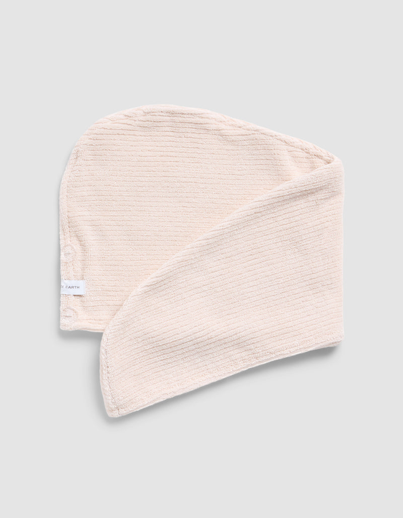 A folded Ribbed Terry Hair towel in Petal on a grey background