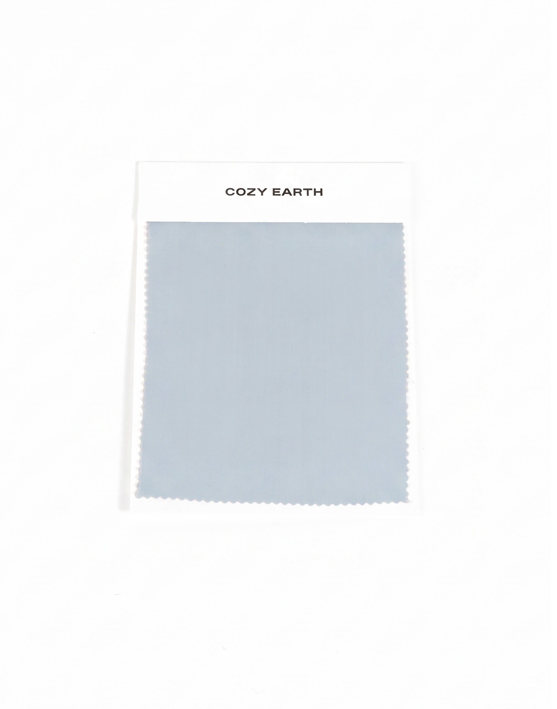 A rectangular light gray-blue Soft-Wash Cotton Sheet Swatch by Cozy Earth is shown on a white card labeled with the brand, set against a plain white background.