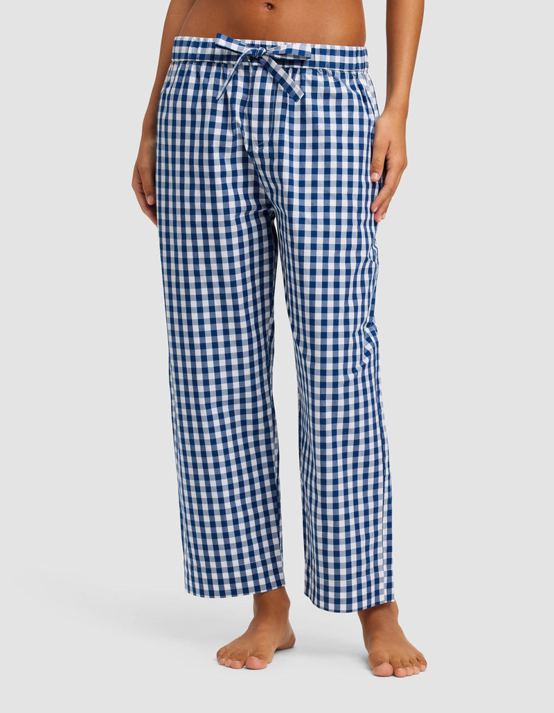 A person models Cozy Earth's Women's Sutton Short Sleeve & Pant Pajama Set—blue and white checkered pants with an elastic waistband and drawstring—standing barefoot against a plain background. The upper body is not shown.
