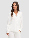 A woman wearing the Cozy Earth Women's Bamboo Stretch-Knit Long Sleeve Pajama Top is smiling while standing against a plain light gray background.|Color:Ivory