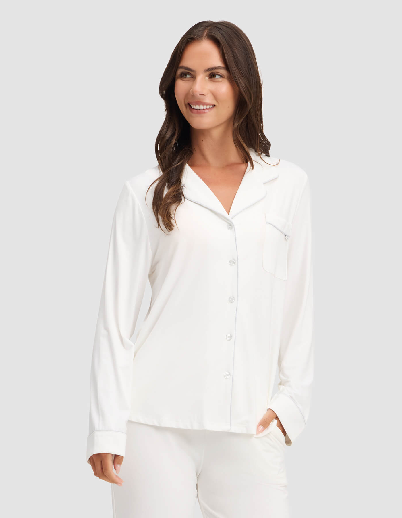 A woman wearing the Cozy Earth Women's Bamboo Stretch-Knit Long Sleeve Pajama Top is smiling while standing against a plain light gray background.|Color:Ivory