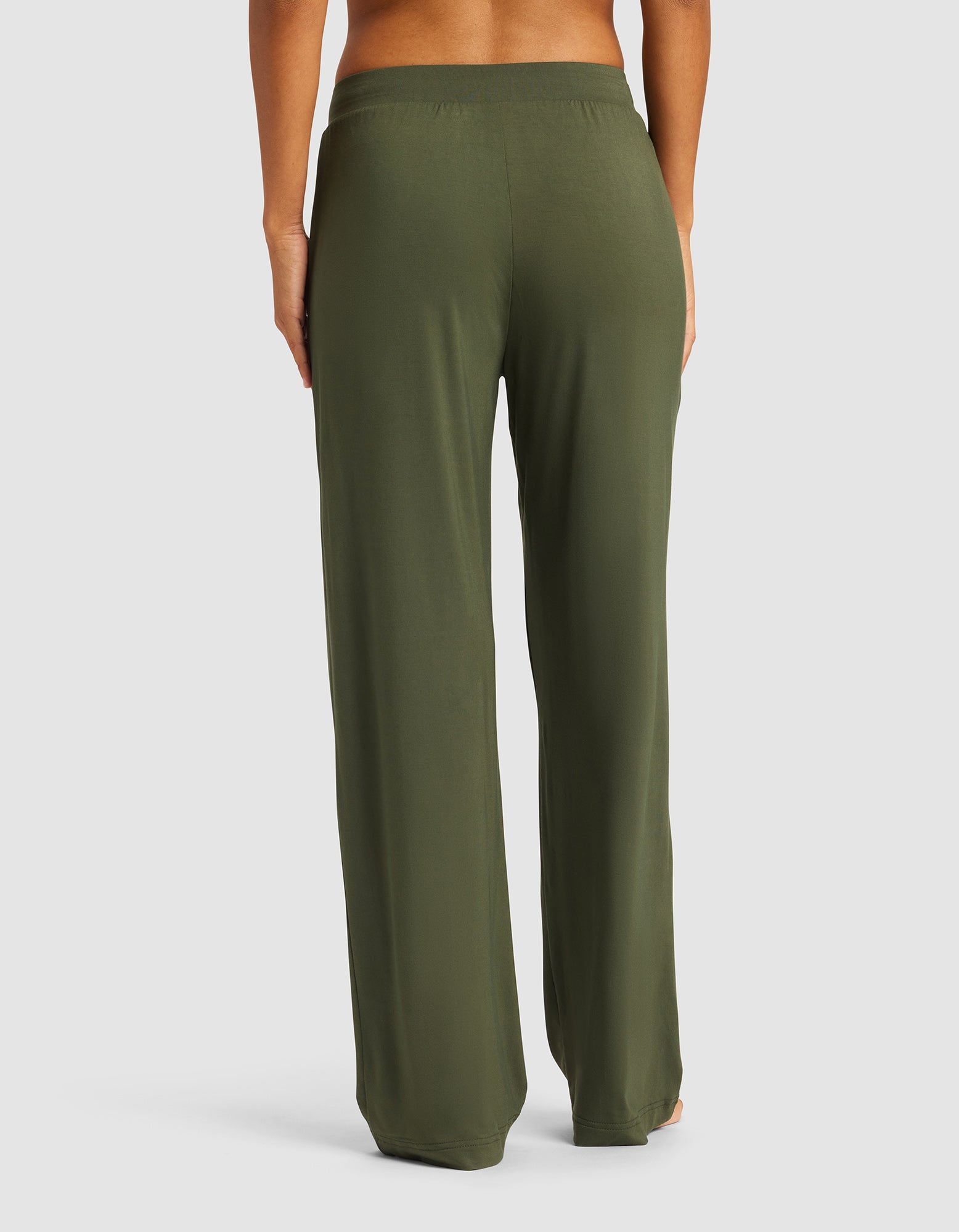 A woman is pictured from the waist down, barefoot against a plain light background, wearing Cozy Earth Women's Bamboo Stretch-Knit Pant in olive green with a relaxed fit.|Color:Olive