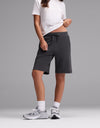 A person wearing a white t-shirt, Cozy Earth Women’s Brushed Bamboo Bermuda Shorts in dark gray, white socks, and gray sneakers stands against a plain gray background. Their face is not visible.|Color:Charcoal