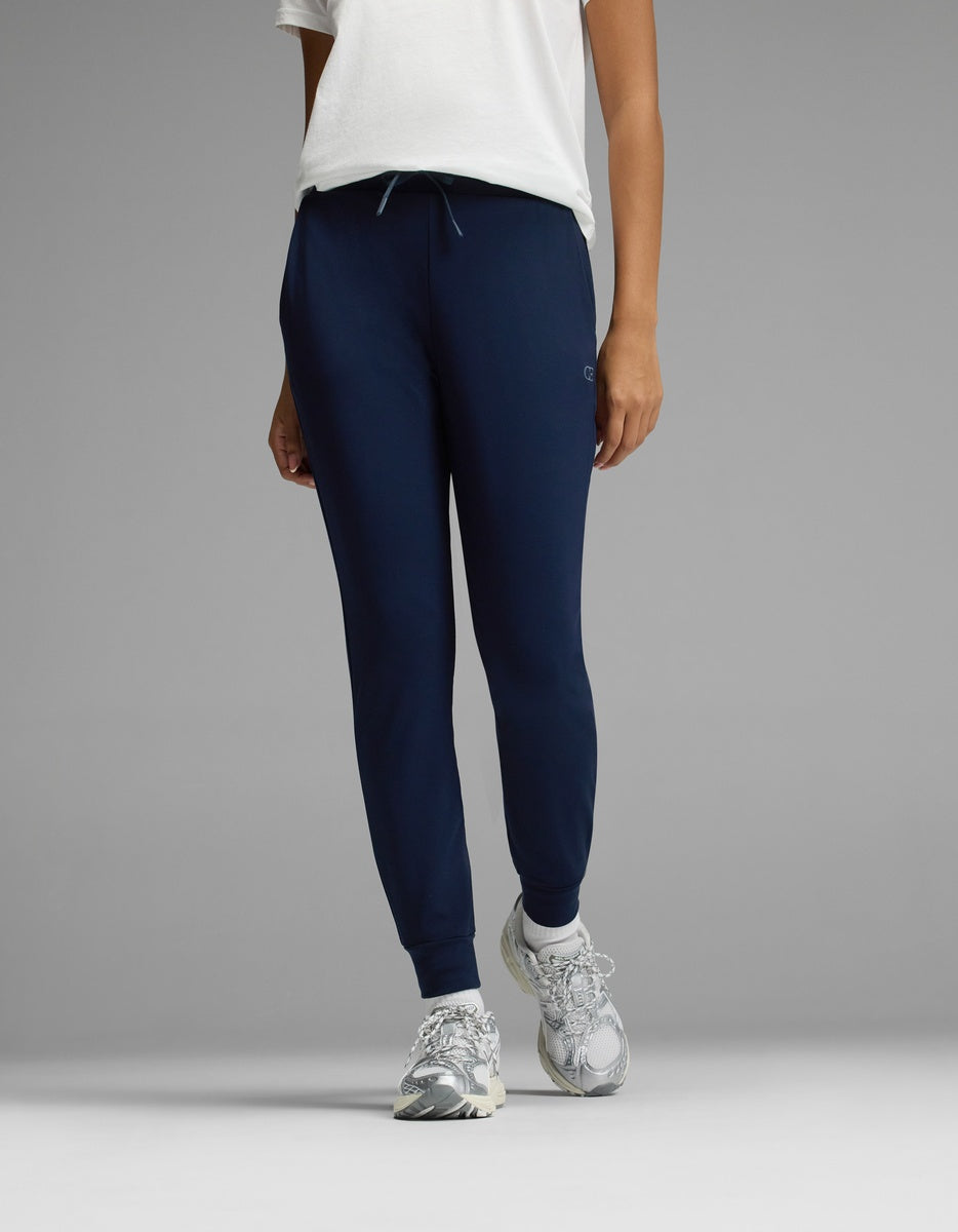 Person wearing a white t-shirt, Cozy Earth Women’s Brushed Bamboo Jogger in navy, and white sneakers, standing against a plain gray background. The image is cropped at the shoulders.|Color:Navy