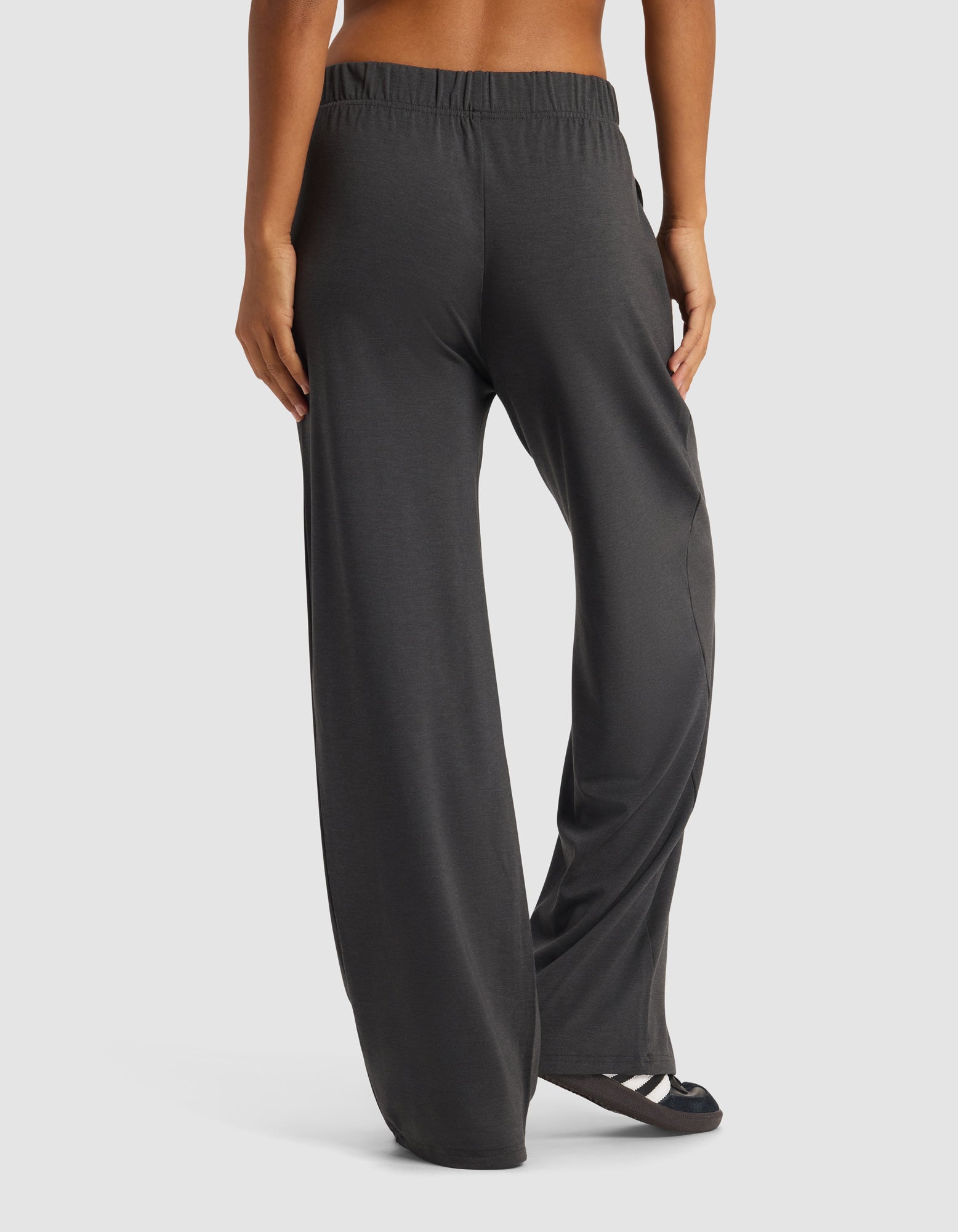 A woman is shown from the back wearing Cozy Earth's Women's Brushed Bamboo Wide Leg Pull-On Pant in dark gray with black sandals, posed against a plain white background.|Color:Charcoal