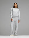 A woman stands facing forward against a plain gray background, wearing Cozy Earth’s Women’s Cityscape Crewneck & Wide Leg Pant Set in Heather Grey, paired with silver sneakers.|Color:Heather Grey