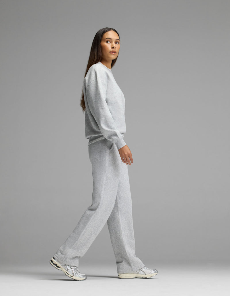 A person wearing the Cozy Earth Women’s Cityscape Crewneck & Wide Leg Pant Set walks to the left against a plain gray background, paired with white sneakers.