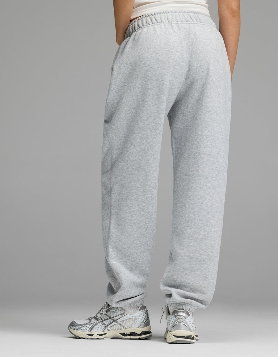 A person dressed in Cozy Earth Women’s CityScape Sweatpant and gray running shoes stands with their back to the camera against a plain background.