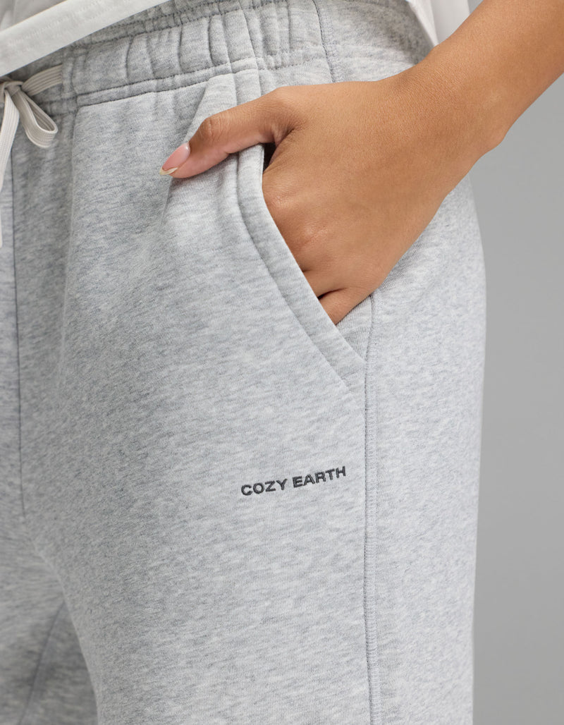 A person wearing the Cozy Earth Women’s Cityscape Wide Leg Pant in light gray, with a hand in the pocket and “COZY EARTH” printed near the pocket.