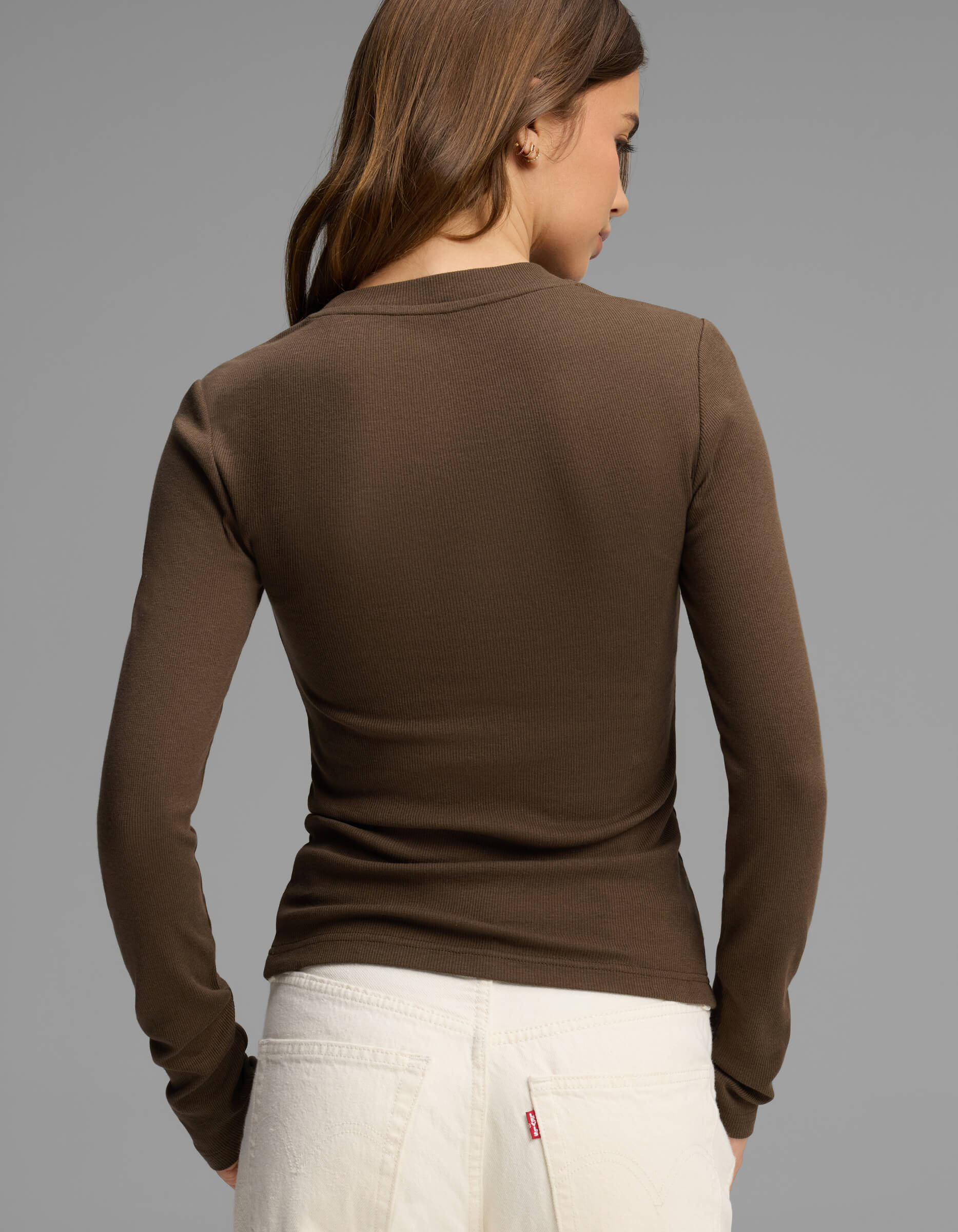 A woman with brown hair, wearing the Cozy Earth Women's Fine Ribbed Long Sleeve Tee in brown and white jeans, is standing with her back to the camera against a plain gray background.|Color:Espresso