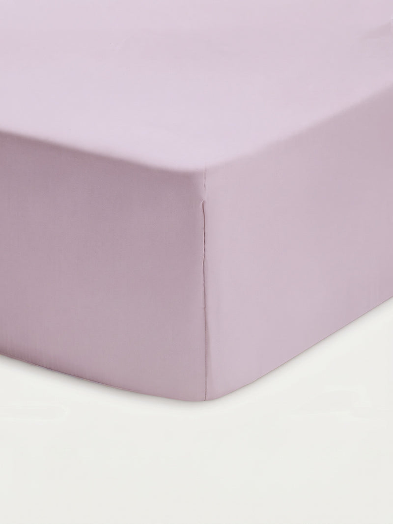 Close-up of the Cozy Earth Bamboo Fitted Sheet in a light lavender hue, snugly covering the corner of a mattress with a smooth, neatly tailored finish against a white background.