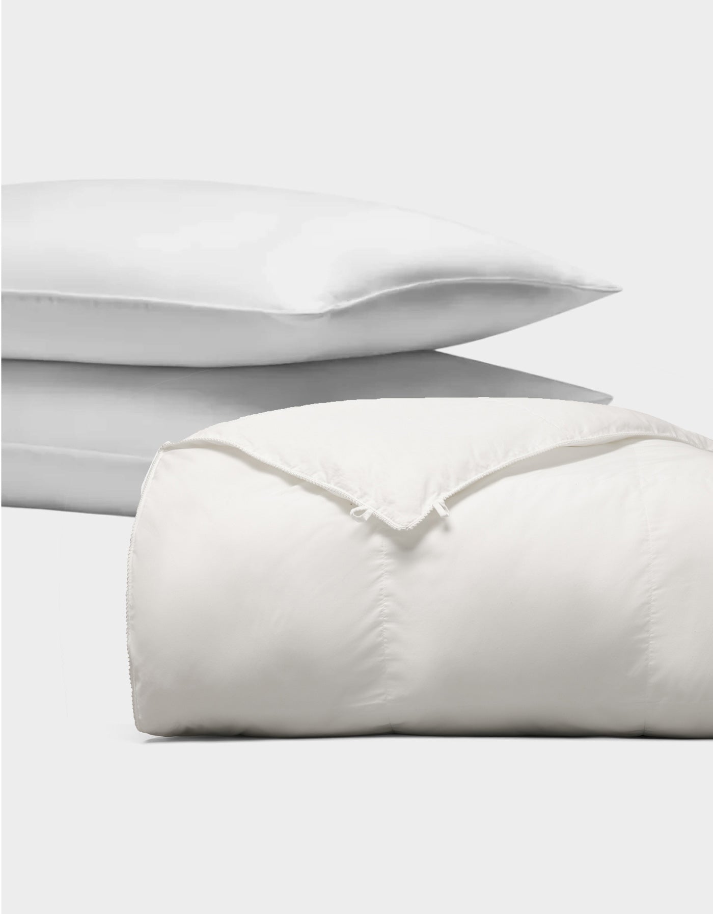 The Cozy Earth Down Alternative Insert Bundle, featuring two stacked white pillows and a folded comforter, is displayed against a plain white background.