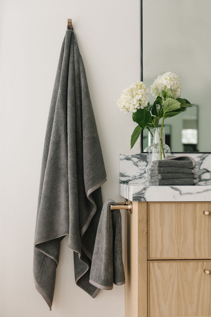 Ribbed Terry Bath Sheets in the color Charcoal. Photo of product taken in a bathroom next to a sink.