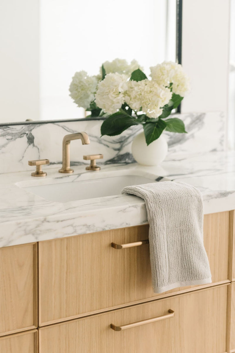 Ribbed Terry Hand Towel in the color White. Photo of Ribbed Terry Hand Towel taken with the Ribbed Terry Hand Towel resting on a bathroom sink.