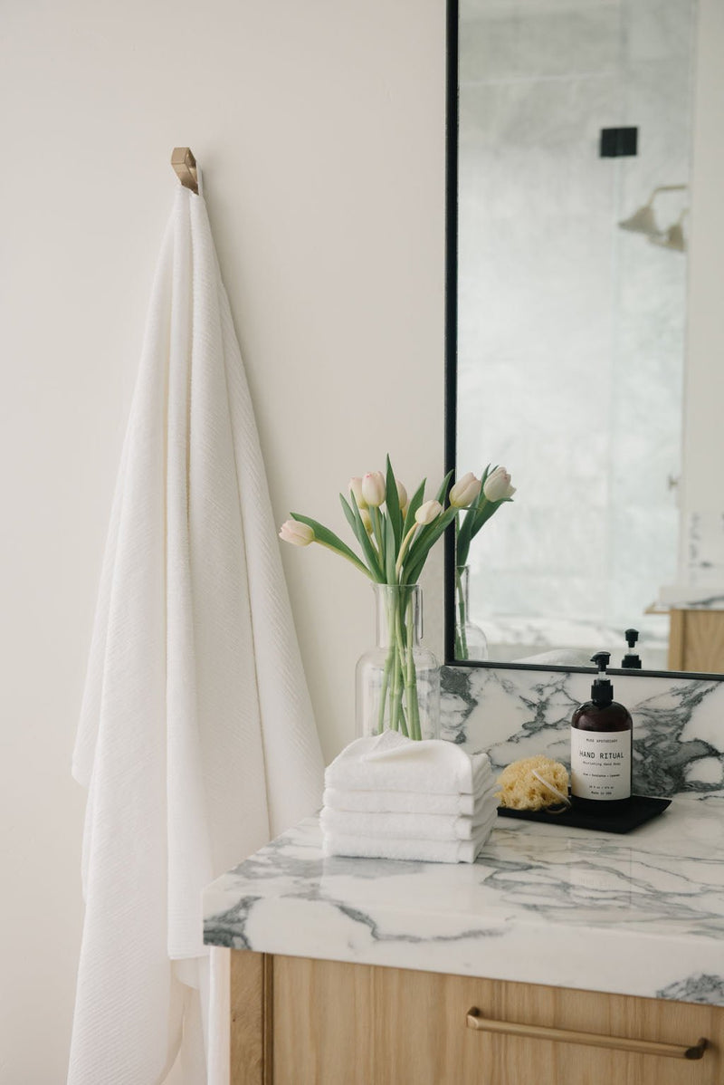 Ribbed Terry Bath Sheets in the color White. Photo of product taken in a bathroom next to a sink.